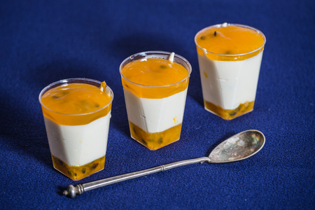 Sweet white chocolate dessert with passionflower cream. Silver spoon on a dark blue background.  Professional bakeryの写真素材