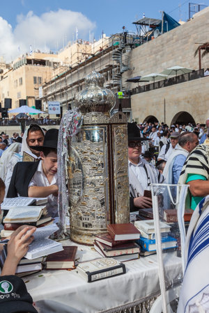 JERUSALEM, ISRAEL - OCTOBER 12, 2014: Morning autumn Sukkot. The area in front of Western Wall of  Temple. Crowd of Jewish worshipers in white wearing prayer shawls. On table there is Torah Roll in magnificent caseのeditorial素材