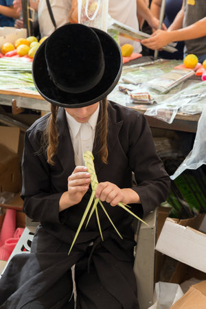 JERUSALEM, ISRAEL - OKTOBER 16, 2016: Traditional market before the holiday of Sukkot. Religious young Jew in a black hat and with side curlsのeditorial素材