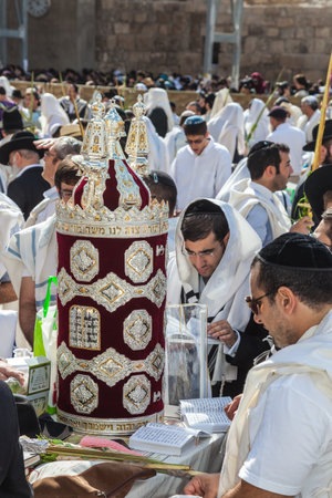 JERUSALEM, ISRAEL - OCTOBER 12, 2014: Morning autumn Sukkot. The area in front of Western Wall of  Temple. Crowd of Jewish worshipers in white wearing prayer shawls. On table there is Torah Roll in magnificent caseのeditorial素材