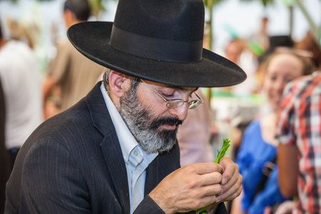 JERUSALEM, ISRAEL - OKTOBER 8, 2014: Traditional market before the holiday of Sukkot. Orthodox men with a white beard in black hat chooses citrus - etrogのeditorial素材