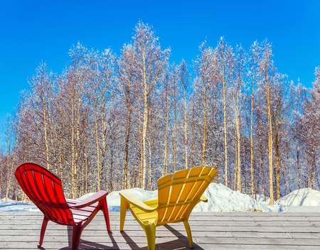 Bright winter frosty day in the Arctic. Comfortable red and yellow plastic chaise lounges for relaxing in forest. The concept of extreme and ecotourism tourismの写真素材