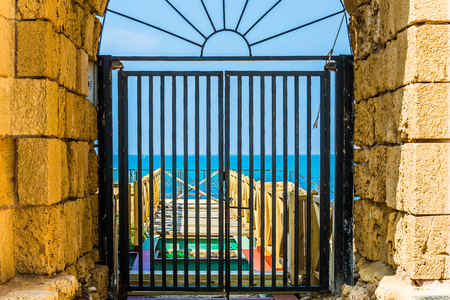 Ruins of the ancient city of Caesarea. The oldest amphitheater in Israel, a fragment of protective walls. Metal gates lock the exit to the sea. Concept of archeological and historical tourismの写真素材