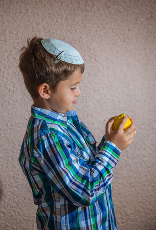  Citrus -  ritual fruit for the Jewish holiday of Sukkot. Beautiful seven year old boy in white knitted skullcap is holding citrusの写真素材