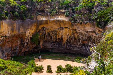 Australia. Tourist -  photographer examines a picturesque cave.The Great Ocean Road goes along the Pacific coast. The concept of photo and active tourismの写真素材