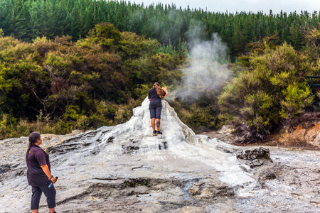 VALLEY OF GEYSERS ROTOROU, NEW ZEALAND - MARCH 24, 2018. The famous geyser of Lady Knox. The girl fills up in a geyser soap mixture to activate the eruption.  Concept of active tourismのeditorial素材