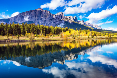 Concept hiking. Canmore, near Banff. Red-orange trees and jagged mountains are reflected in the  lakeの写真素材