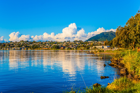 Fabulous summer sunset at Lake Taupo. Lush clouds and blue sky are reflected in the smooth water of the lake. The concept of active and phototourismの写真素材