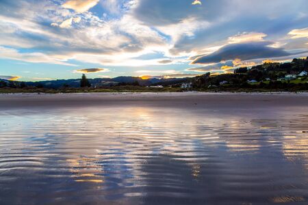 Sunset over the ocean, last ray. Gorgeous sunset colors are reflected in the ocean water. The art of artistic photography. New Zealand, Pacific Coast. The concept of ecological and photo tourismの写真素材
