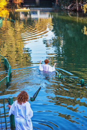 YARDENIT, ISRAEL - JANUARY 21, 2012: Christian pilgrims baptized in the Jordan River. They enter the water, dressed in special white robesのeditorial素材