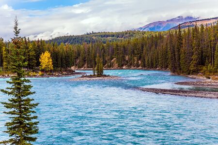 Large lake among the mountains and colorful autumn coniferous forests. Journey to the mountain fairy tale. The concept of active, eco-and photo-tourismの写真素材