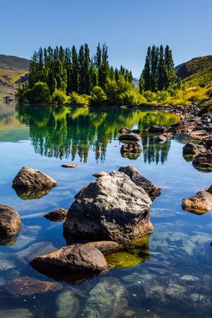 Cypress alley and huge basalt boulders reflected in the lake. The surroundings of the Cromwell....