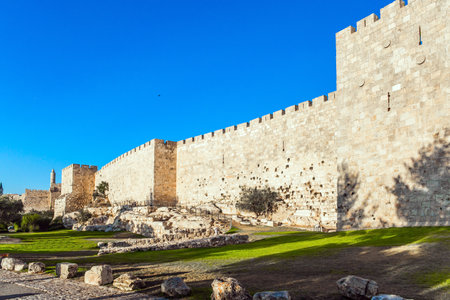 Summer sunset. The fortress wall of ancient Jerusalem. Old Citadel - Tower of David. Adorable green lawn growing under ancient walls. The concept of historical, pilgrim and photo tourismのeditorial素材