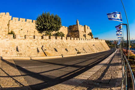 Hot summer sunset. Powerful double protective walls are illuminated by the sunset. The highway surrounds the Old City of Jerusalem. The concept of religious, historical and photo tourismのeditorial素材