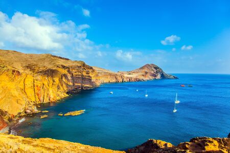 The west coast of Madeira - the bay between the rocks with yachts and boats. Madeira is island in the Atlantic. The blinding midday sun. The concept of active, ecological and photo tourismの写真素材