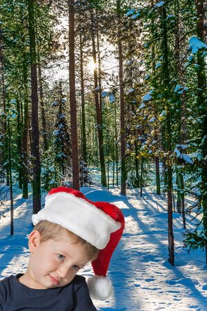 Handsome little boy with blue eyes is sad. Lapland. The snow-covered coniferous forest. The concept of extreme and active tourismの写真素材