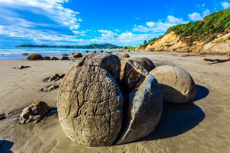 Huge cracked boulder on Moeraki beach. New Zealand. Low tide in the Pacific ocean. The popular tourist attraction. The concept of exotic and ecological tourismの写真素材