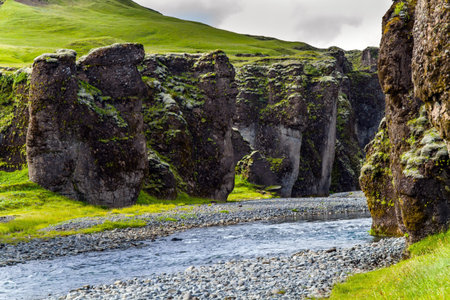 The beginning of the canyon. Sheer cliffs stand along a stream with melted glacial water. The...