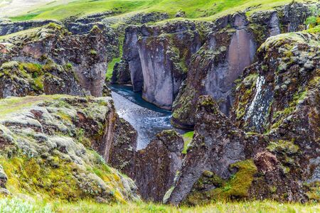 The Fyadrarglyufur Canyon, Iceland. Sheer cliffs covered with green moss. River with glacial water flows between bizarre cliffs. The concept of active, eco and photo tourismの写真素材