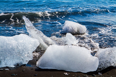 Ocean surf brings ice floes. The famous icelandic black sand beach. North Atlantic. The lagoon...
