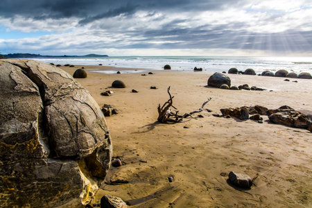 Moeraki boulders is a group of huge stones and their remains. Low tide in Pacific ocean. The South Island of New Zealand. The popular tourist attraction. The concept of exotic and ecological tourismの写真素材