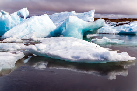 Iceland. The largest glacial lagoon Jokulsaurloun. The ice is covered in black and braun volcanic ash in some places. Cold early summer morning. The concept of extreme, northern and photo tourismのeditorial素材