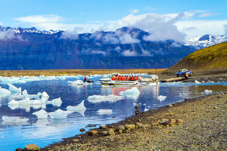ICELAND, SCAFTAFETL PARK, ICE LAGOON JOKULSAURLOUN - July 10, 2014: The icebergs and ice floes. Picturesque yellow boat for a sightseeing tour. The concept of northern and photo tourismのeditorial素材
