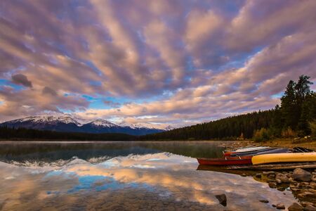Majestic lake Patricia at sunrise. Red canoe sports boats are dried by the lake. Jasper Park. Rocky Mountains of Canada. The concept of active, northern and photo tourismの写真素材