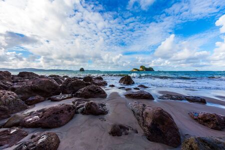 Picturesque huge boulders on a sandy beach. New Zealand. Cathedral Cove on Coromandel Peninsula at sunset. The evening tide begins. The concept of exotic, ecological and photo tourismの写真素材