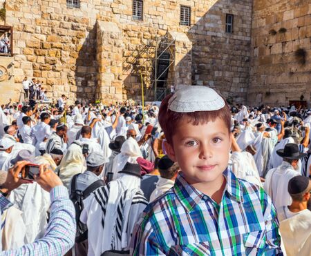 Handsome Jewish boy in yarmulke. Jews praying at the Western Wall. The blessing of the Cohen. Solemn ceremony at the Western slope of the Temple Mount in Jerusalem. The concept of religious and photo tourismの写真素材