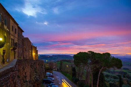 The edge of the sky turns pink. The stunning landscape of valley is photographed from a protective wall around the city. Tuscany. The concept of active, architectural and photo tourismの写真素材