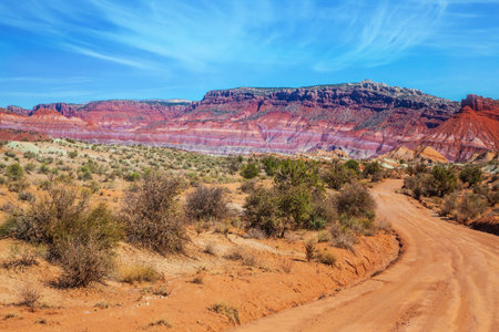 Red sandstone dirt road. Huge slopes of red sandstone, striped from various inclusions of light rocks. Paria Canyon-Vermilion Cliffs Wilderness Area. The concept of extreme and photo tourismの写真素材