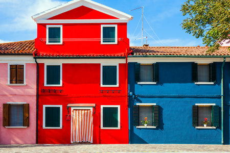 The small picturesque island of Burano near Venice. Facade of a lovely red and blue colored house. The concept of cultural, historical and photo tourismのeditorial素材