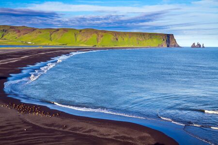 Cape Dyrholaey. Travel to the fabulous island of Iceland. The southern edge of Iceland. Beach with black volcanic ash Reinisfjara. The concept of active, extreme and photo tourismの写真素材