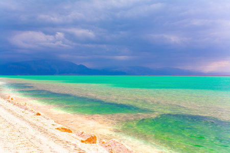Low winter clouds are reflected in the green sea water. The landfill embankment runs through the...