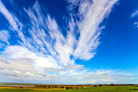 The southernmost point of New Zealand. Incredible sky and clouds of summer sunset. Southern Scenic Route. Green fields are surrounded by trees. South Island of New Zealandの写真素材