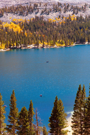 Orange, yellow and red leaves of birches and aspens. Rock Creek road lakes. Magnificent oval lake with blue water is surrounded by picturesque mountains. Lush autumn in Montana, USAの写真素材