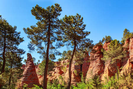Provence, France. The village of Roussillon. Bizarre red rocks. Walk along the most beautiful red-yellow-orange route. The rocks are covered with forest. Sunny and warm day.の写真素材