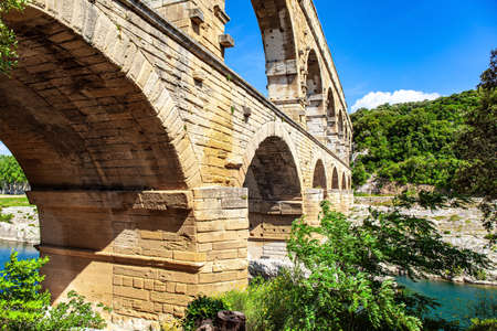 Picturesque antique bridge - aqueduct. The Pont du Gard is the tallest Roman aqueduct. Interesting trip to France. The shallow Gardon River. Bright sunny dayの写真素材