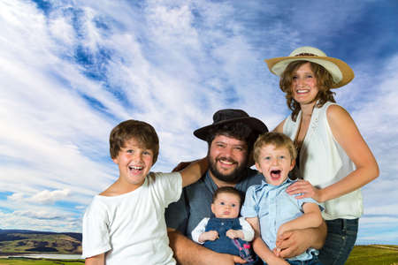 Happy family on vacation. Young beautiful parents - mom and dad, two sons - a schoolboy and a little daughter - baby. Background sky and cirrus clouds. Concept - portrait and advertising photoの写真素材