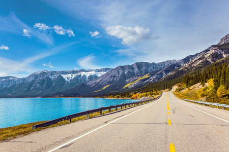 Magnificent Indian summer in the Canadian Rockies. Asphalt highway leads to Abraham Lake. The first snow has already fallen on the peaks of Canadian Rockies.の写真素材