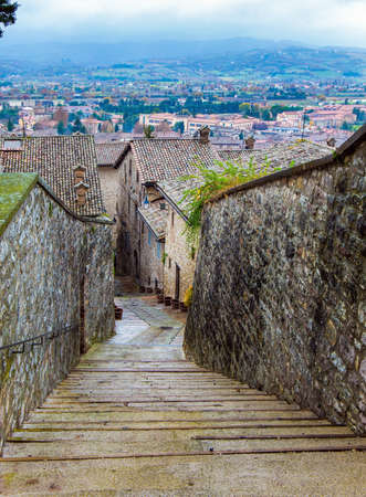 The city of Gubbio is located in the Umbrian mountains. Ancient city with a rich history. Narrow cobblestone trail leads to the top of the hill. Autumn cloudy day. Magnificent Italyの写真素材