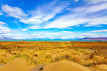 Argentine Patagonia. The endless flat prairie is overgrown with yellow autumn grass. Whimsical clouds over the lake. Lake in the steppe.の写真素材