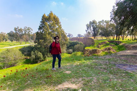Elderly woman taking pictures of beautiful nature. Early spring in Israel. Kibbutz Beeri. Green...