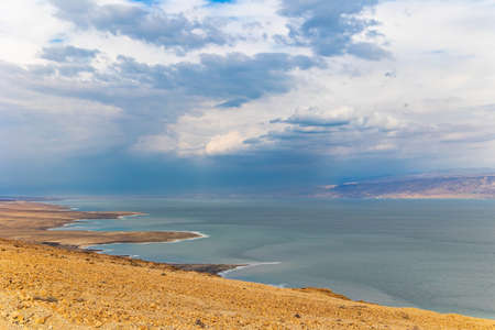 The great wonder of nature is the Dead Sea. Cloudy and clear January day. The sea surface reflects the clouds. Israeli coast. Jordan on the opposite coast of the sea is illuminated by the dim winter sun.の写真素材