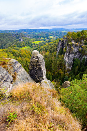 Romantic trip to Saxon Switzerland. Spectacular sandy cliffs of Bastei over the Elbe River.  Picturesque dizzying landscape. Cloudy autumn day. Germany.の写真素材