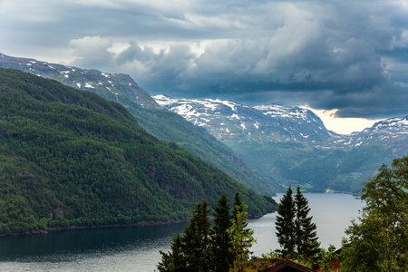 Kinsarvik - village at the confluence of two fjords. Summer. Western Norway. Beginning of the Hardangerfjord. Powerful clouds are reflected in the fjord.の写真素材
