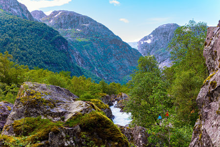 Gorgeous mountainous Norway. Rumbling turbulent foamy stream of cold water flowing from the lake Bondhuswatnet. Emerald green of summer grass.の写真素材