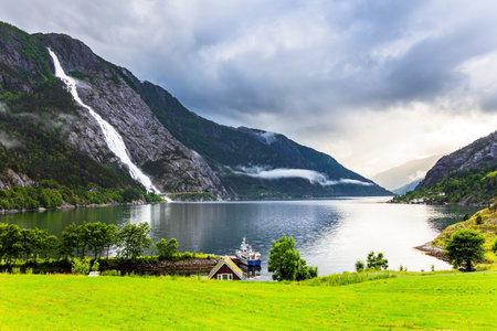 Majestic natural phenomenon. Magnificent giant Langfossen waterfall intersects with the highway and flows into the Acre Fjord.  Rainy cold July in Norway.の写真素材
