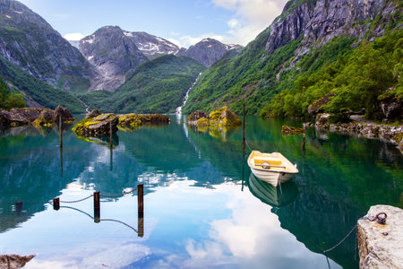 Gorgeous mountainous Norway. The lake Bondhuswatnet. Picturesque small boat is moored not far from the shore. The boat is reflected in the clear water of the lake.の写真素材